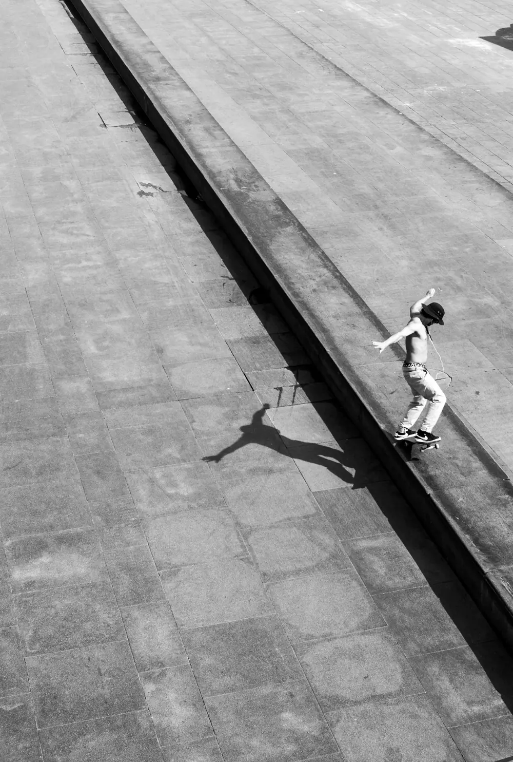 Overhead view of a skateboarder on a wide concrete ledge